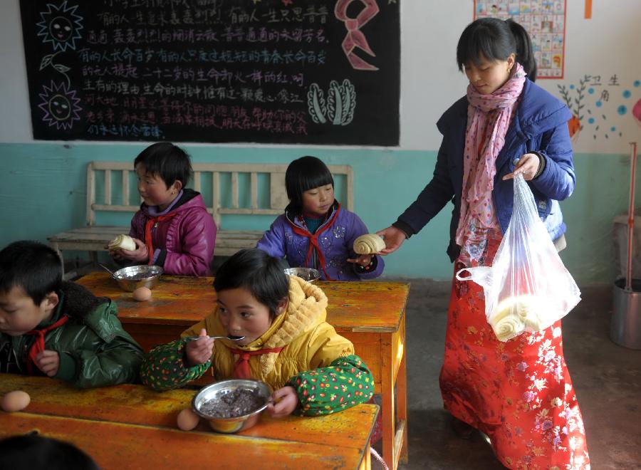 Yang Yan (1st R), a techer, helps distribute food for students at lunch time at the classroom of Shimen central primary school in Tianzhu Tibetan Autonomous Prefecture, northwest China's Gansu Province, March 12, 2012. 
