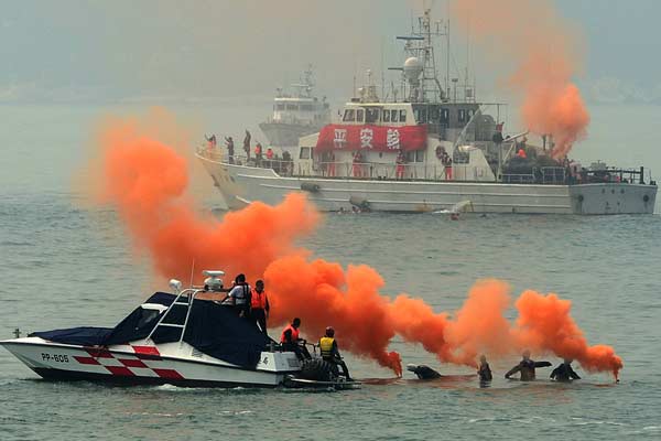 Dummy “passengers” drop orange smoke grenades into the water to call for help during a joint sea search and rescue drill between the mainland and Taiwan in the Taiwan Straits on Thursday. [ Photo / China Daily ]