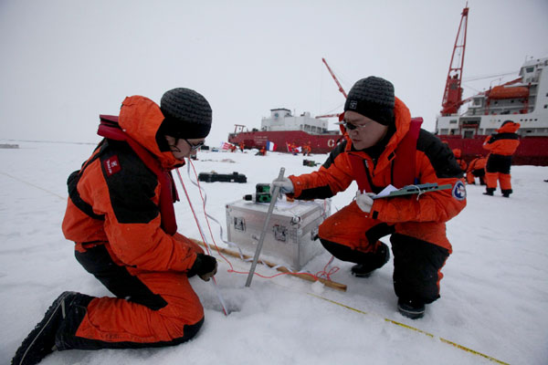 Two scientific researchers measure the thickness of the ice at a temporary station in the Arctic Ocean, Aug 29, 2012. China started its fifth arctic expedition on July 2. [Photo/Xinhua]