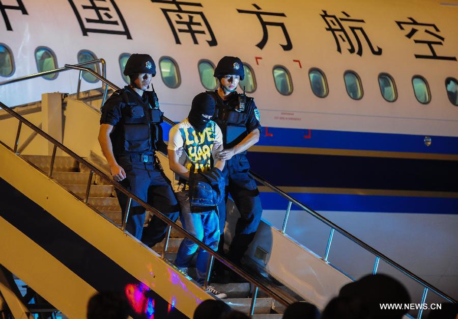Suspect Xiong Yi (C) is sent from an airplane under escort in Wuhan, Hubei Province, on Sept. 2, 2012. Chinese police have seized him for allegedly sending a threatening message which caused a domestic flight to divert on Thursday. Xiong was caught Saturday afternoon in a hotel in Dongguan, Guangdong.