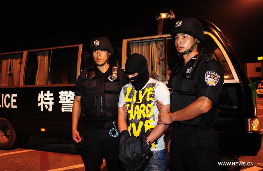 Suspect Xiong Yi (C) is sent from an airplane under escort in Wuhan, Hubei Province, on Sept. 2, 2012. Chinese police have seized him for allegedly sending a threatening message which caused a domestic flight to divert on Thursday. Xiong was caught Saturday afternoon in a hotel in Dongguan, Guangdong.