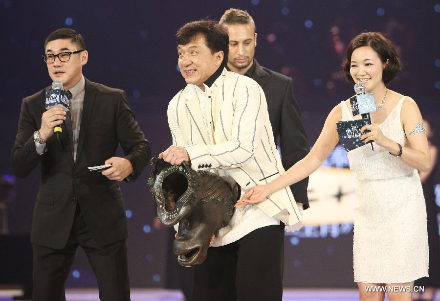 Actor Jackie Chan (C) carries an auction object to show to audience at the 2012 BAZAAR Stars Charity Night in Beijing, China, Sept. 1, 2012. Chinese showbiz stars, entrepreneurs and celebrities attended the event which raised more than 40 million yuan (US$6.3 million) in Beijing on Saturday. 