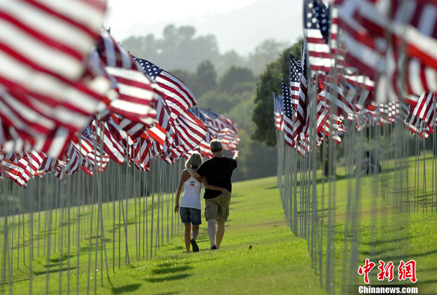 People walk amongst US national flags erected by students and staff from Pepperdine University to honor victims of the 9/11 attacks, in Malibu on September 9, 2012. 