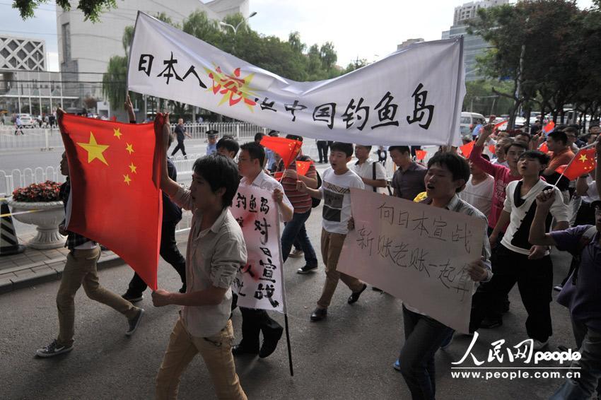 Demonstrators hold banners (territorial integrity and protection of Diaoyu Islands in Chinese) and chant slogans as they protest outside the Japanese embassy in Beijing on Setp. 13, 2012. [Photo/people.com]
