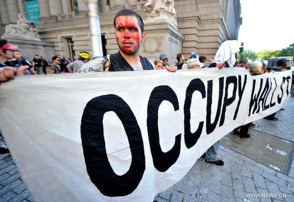 Members of 'Occupy Wall Street' hold up a banner during the one-year anniversary of the movement in New York, the United States, on Sept. 17, 2012. 