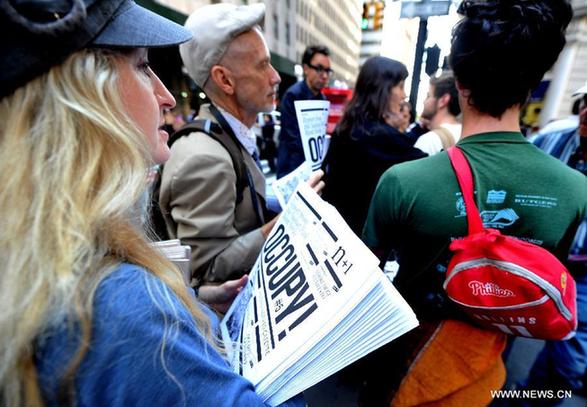 A member of 'Occupy Wall Street' distributes handbills during the one-year anniversary of the movement in New York, the United States, on Sept. 17, 2012. 