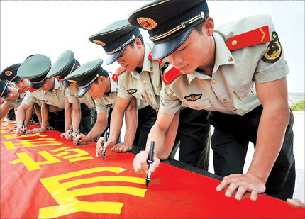 Frontier officers autograph a banner that says 'Remember history, rejuvenate China' at a town in Taizhou City, Zhejiang Province, yesterday ahead of today's observation of the 81st anniversary of Japan's invasion of China's northeast. Several major Japanese businesses are shut today fearing further nationwide protests over Japan's Diaoyu Islands 'purchase.'[Photo/Shanghai Daily]