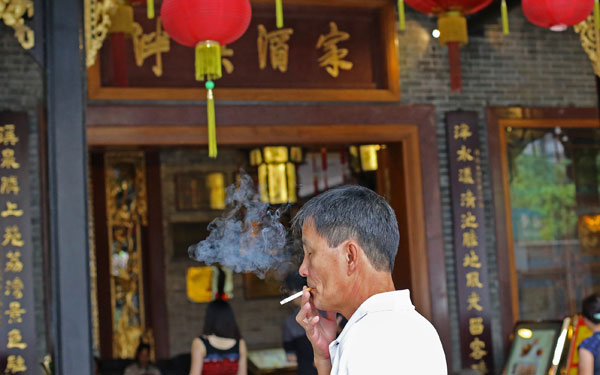 A local restaurant customer lights up outside an establishment after Guangzhou ruled that smoking in banned areas, including inside a restaurant, could be fined 50 yuan effective the beginning of this month. 