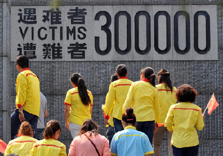 Visitors walk in front of a wall in which the number of victims is displayed, at the Memorial Hall of the Victims in Nanjing Massacre by Japanese Invaders in the capital of Jiangsu province on Tuesday.[Photo/Xinhua]