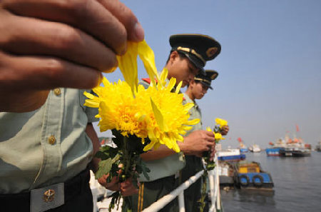 Military personnel throw chrysanthemums into the sea on Tuesday to remember those who lost their lives fighting against the Japanese invaders.[Photo/China Daily]