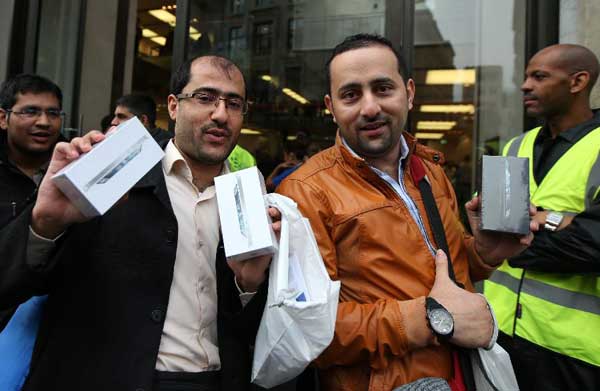 The first customers of the Apple Inc. iPhone 5 hold up their purchases after exiting the Apple Retail Store at Regent Street in London, Britain on September 21, 2012. The new released phone is on sale from Friday in Britain. [Wang Lili/Xinhua]