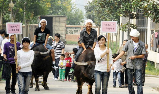 College students in Hefei, Anhui province, ride on buffaloes to promote awareness for World Car Free Day on Saturday. [China Daily] 