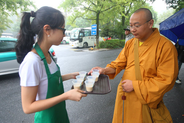 A Starbucks waitress serves a monk coffee on Saturday. The US coffee giant Starbucks has opened a cafe shop close to the Lingyin Temple, a Buddhist temple in Hangzhou, capital of Zhejiang province, giving rise to controversy. Some say Starbucks is bringing the 'stench of money' to the temple. Others say it is only bringing Western culture into proximity with Chinese culture. [Photo/CFP] 