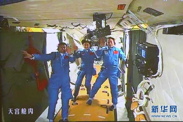 6月18日拍摄的北京航天飞控中心大屏幕显示的航天员景海鹏、刘旺、刘洋在天宫一号实验舱内的画面。