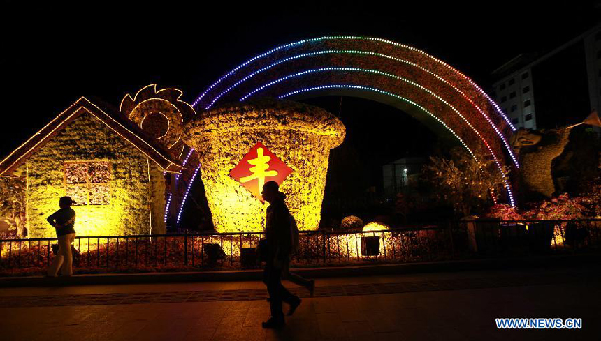 Citizens walk past the flower decorations in Beijing on the evening of Sept. 28. Flowers are laid on the city&apos;s streets and squares to greet the upcoming National Day on Oct. 1.