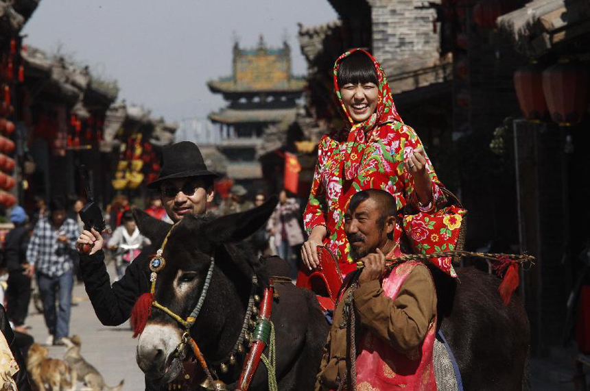 Tourists pose for photo in Pingyao Ancient City, north China&apos;s Shanxi Province, Sept. 28, 2012. The cultural tourism programs promoted by Jinzhong City have attracted many visitors from home and abroad. 