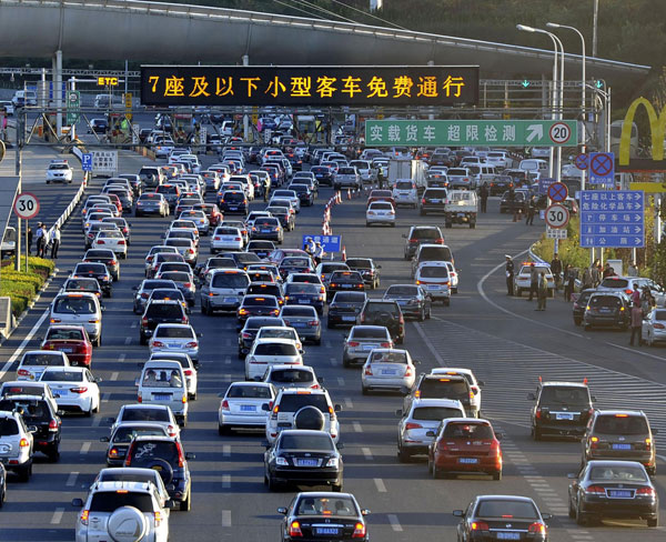 Vehicles line up to pass a toll station in Dalian, Northeast China's Liaoning province, Sept 30, 2012. The flow of traffic on expressways is estimated to increase after the country lifted road tolls for cars using highways during major Chinese holidays. [Photo/Xinhua] 