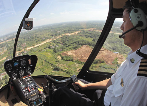 A pilot with Ruohang Transportation Development Co flies a helicopter. [Photo/China Daily] 