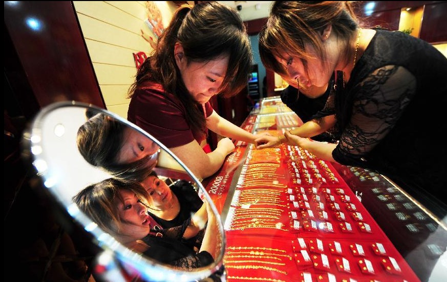 A customer selects gold jewelry at a shop in Yantai, east China's Shandong Province, Oct. 2, 2012. People around China enjoy themselves in various ways during the Mid-Autumn Festival and Chinese National Day holiday, which lasts from Sept. 30 to Oct. 7.[Photo/Xinhua]