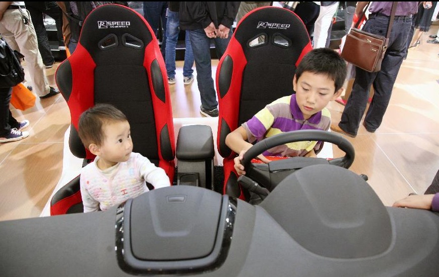 Two children are seen on a car at the 11th Nanjing Automobile Expo in Nanjing, capital of east China's Jiangsu Province, Oct. 2, 2012. People around China enjoy themselves in various ways during the Mid-Autumn Festival and Chinese National Day holiday, which lasts from Sept. 30 to Oct. 7. 