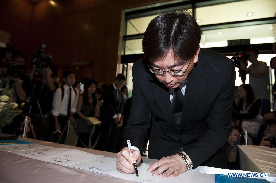 The secretary for the food and health department of Hong Kong Ko Wing-man signs at a condolence place in Wanchai of Hong Kong, south China, Oct. 4, 2012. Eighteen condolence places were set up in Hong Kong Thursday to mourn for the victims of the ferry accident during which thirty-eight people including at least five children were killed. 