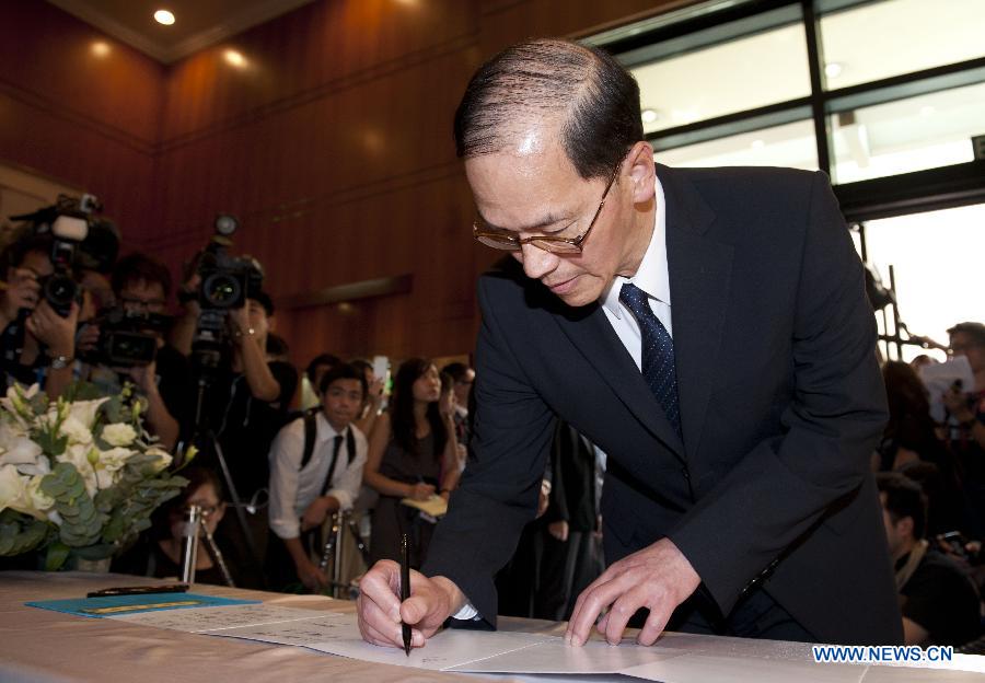 Secretary for Home Affairs of Hong Kong Tsang Tak-sing signs at a condolence place in Wanchai of Hong Kong, south China, Oct. 4, 2012. Eighteen condolence places were set up in Hong Kong Thursday to mourn for the victims of the ferry accident during which thirty-eight people including at least five children were killed.