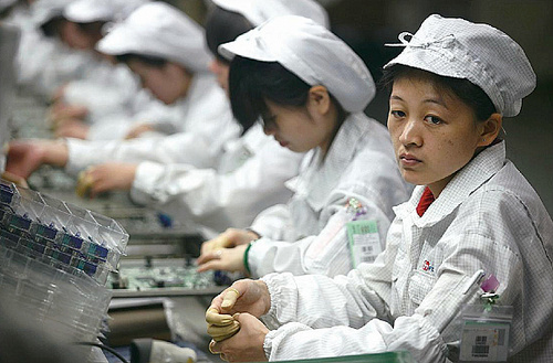 Workers attend to electronic parts at a Foxconn plant. [File photo] 