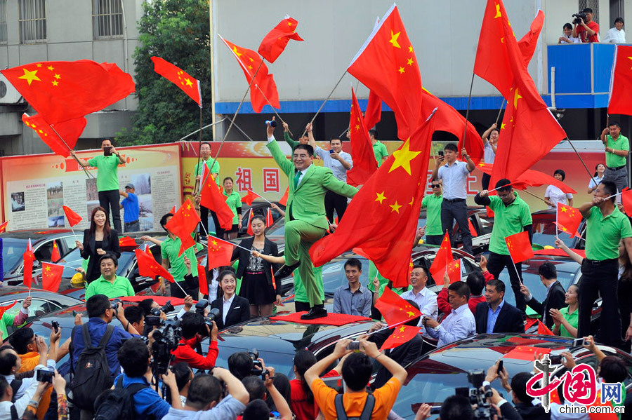 2012年10月10日，南京，陈光标举行以旧车换新车仪式，43个在抗议钓鱼岛事件中被砸的日系车主获得了陈光标赠送的国产吉利帝豪汽车。图为陈光标站在车顶上又唱又跳。图片来源:XPP/CFP