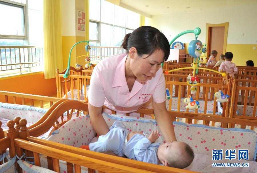在潍坊儿童福利院，杨守伟在照顾孤残儿童（9月26日摄）。[新华社]