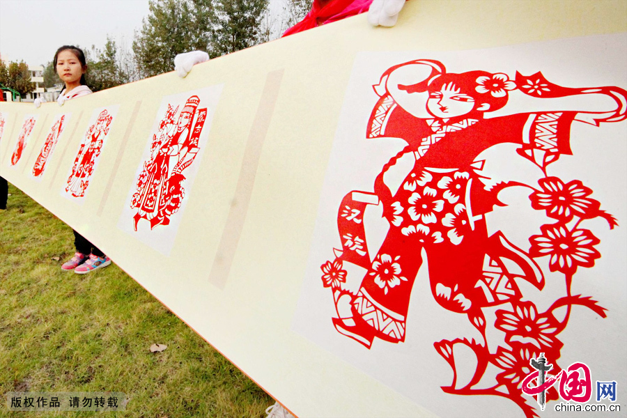 10月9日，江苏省赣榆县罗阳镇中心小学校园的操场上，学生们正在展示长达38.8米的《和谐中国》刻纸长卷。[中国网图片库 司伟 摄影]