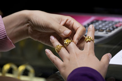 A woman trying on gold rings in a Chow Tai Fook Jewellery Group store in Hong Kong. [Photo/China Daily]