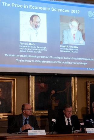 Winners of the 2012 Nobel Prize in Economic Sciences, American economists Alvin Roth (L) and Lloyd Shapley, are presented on a screen during a press conference held by the Royal Swedish Academy of Sciences in Stockholm, Sweden, on Oct. 15, 2012. [Liu Yinan/Xinhua]