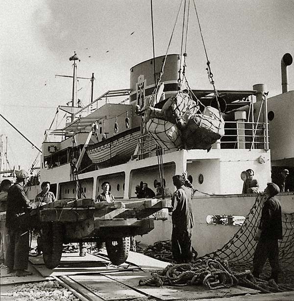 Workers unload goods from a ship in Tianjin Port after its reopening in the 1950s. [File photo/Xinhua] 