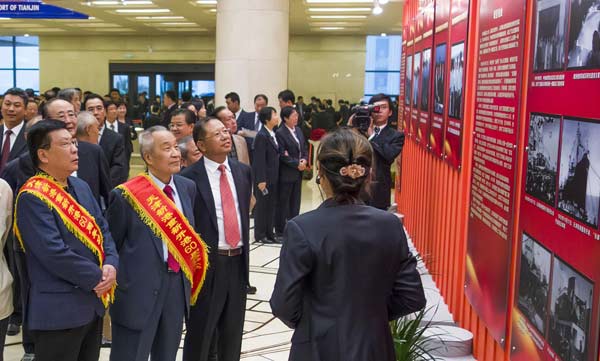 Visitors look at photos in an exhibition of the 60 years' development of Tianjin Port in Tianjin, Oct 17, 2012. [Photo/Xinhua] 