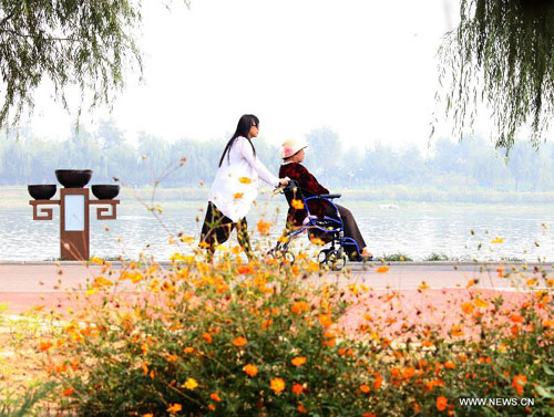 An elderly citizen, accompanied by her family, visits a park in Beijing, capital of China, Oct. 2, 2012. During the 8-day-long holiday, many aged people in China enjoy themselves by traveling. [Photo/Xinhua]
