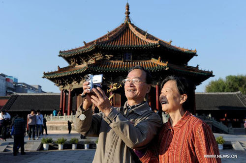 An elderly couple take pictures at the Forbidden City in Beijing, capital of China, Oct. 4, 2012. During the 8-day-long holiday, many aged people in China enjoy themselves by traveling.[Photo/Xinhua]