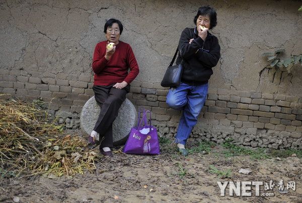 2012年10月15日，高密市大栏乡平安庄，莫言旧居，院内，从青岛市赶来的李秀云和李贞云靠着围墙休息时吃零食，她们说，非常佩服莫言，看过红高粱电影。