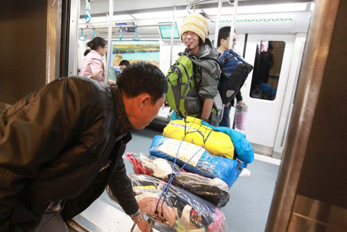A Beijing resident helps Japanese cyclist Kawahara Keiichiro unload relief resources from a subway car, before his flight to a quake-hit area in southwest China's Yunnan Province on Wednesday, October 24, 2012. [Photo/CFP]