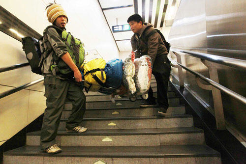 A Beijing resident helps Japanese cyclist Kawahara Keiichiro carry relief resources in a subway station, before his flight to a quake-hit area in southwest China's Yunnan Province on Wednesday, October 24, 2012. [Photo/CFP]