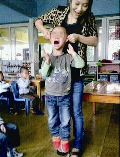 A female kindergarten teacher surnamed Yan in east China's Zhejiang Province holds up a boy by his ears. 