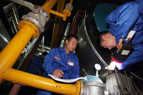 Workers perform a final round of tests on heating pipes and equipment in a boiler room in Beijing on Tuesday. [China Daily] 