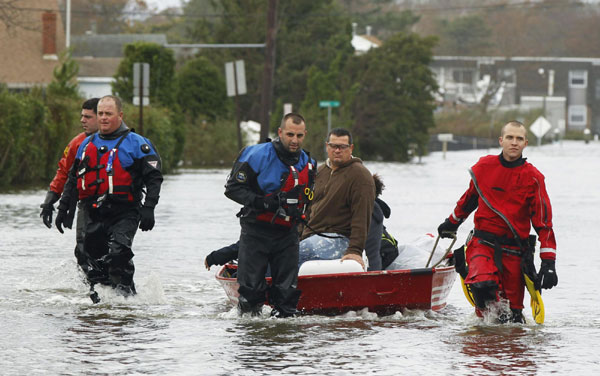 Members of the Patchogue Fire Department escort stranded residents from their homes on a boat in Patchogue, New York, October 30, 2012. [Agencies] 