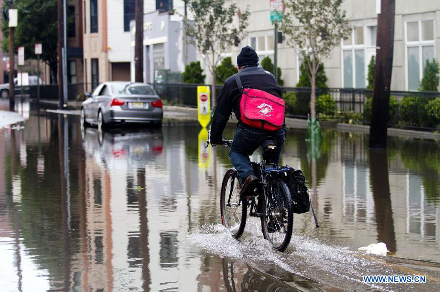 A resident rides a bike on a flooded street in Hoboken of New Jersey, the United States, on Oct. 31, 2012. Hurricane Sandy lashed the U.S. east coast and made a landfall in New Jersey Monday evening, knocking out power for millions and killing at least 64 people. 