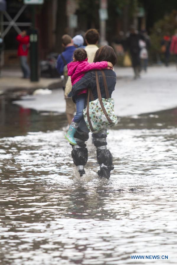 People walk on a flooded road in Hoboken of New Jersey, the United States, on Oct. 31, 2012. Hurricane Sandy lashed the U.S. east coast and made a landfall in New Jersey Monday evening, knocking out power for millions and killing at least 64 people.