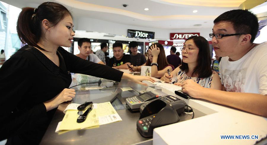 Tourists pay for cosmetics they select at a duty free shop in Sanya, south China&apos;s island province of Hainan, on Oct. 31, 2012. 