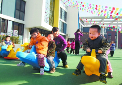 Children and teachers play games on the playground in a preschool in Haidian District, Beijing. [File photo]  