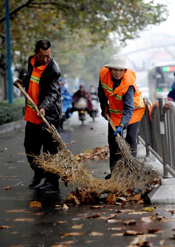 Municipal workers clear leaves on a road in Zhengzhou, capital of central China's Henan Province, on Nov. 3, 2012.