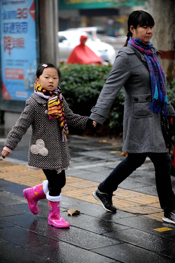 Residents wearing warm clothes walk in Zhengzhou, capital of central China's Henan Province, on Nov. 3, 2012. 