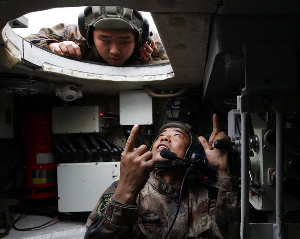 Jia Yuanyou, a delegate of the 18th CPC National Congress and artilleryman, points up to the mechanics for another soldier in Beijing, Nov 24, 2011.[Xinhua]