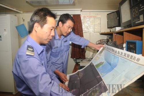 Chinese fishery officials look at a map of the Diaoyu Islands aboard a patrol ship in waters off the islands on October 22 [YANG JINZHI]
